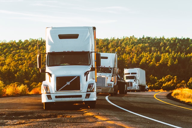 Multiple white Volvo Semi-trucks on the side of road